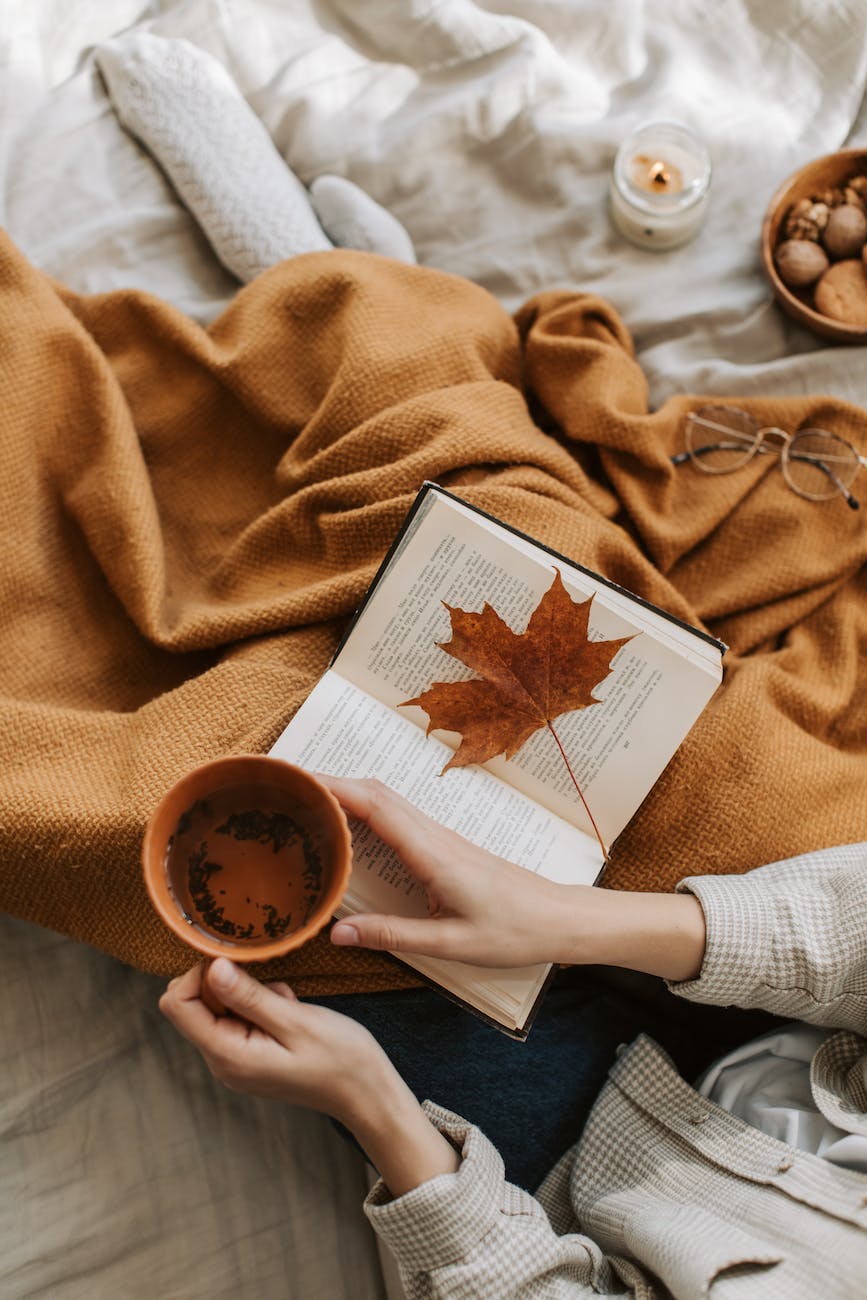 person covered in brown blanket holding a mug